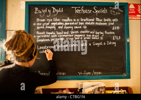 Writing the daily specials menu on the blackboard at The Treehouse organic vegetarian cafe restaurant, Aberystwyth Wales UK Stock Photo