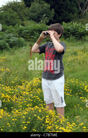 Boy bird watching in a meadow; Cornwall; UK Stock Photo