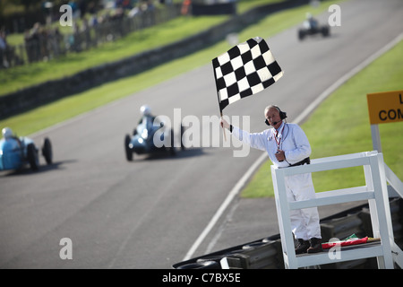 Cars speed past the checkered flag at the Goodwood Revival Meeting 2011. Picture James Boardman. Stock Photo