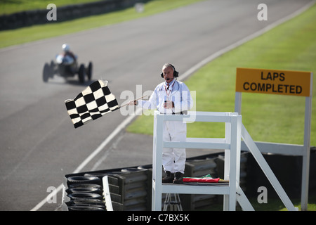 Cars speed past the checkered flag at the Goodwood Revival Meeting 2011. Picture James Boardman. Stock Photo