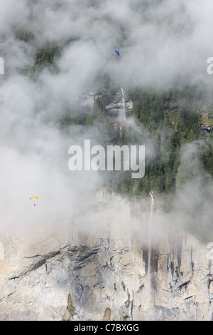 Two skydivers / parachutists soaring by the magnificient Staubbachfall waterfall above the Lauterbrunnen Valley. Bern, Switzerland. Stock Photo