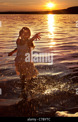 little happy girl splashing water in the lake Stock Photo