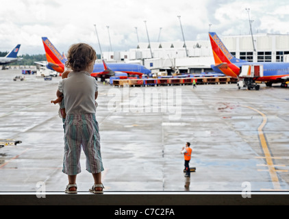 Girl with doll watching airplanes at airport, Sea Tac, Seattle, Washington, USA Stock Photo