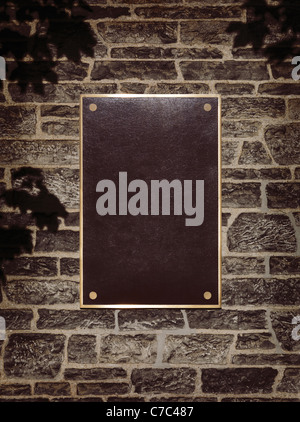 Blank sign in shiny metal frame on a stone wall Stock Photo