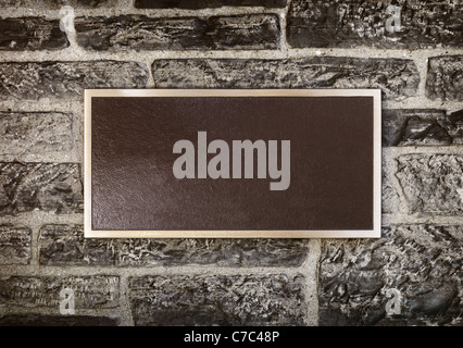 Blank sign in shiny metal frame on a stone wall Stock Photo