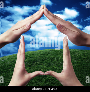 Conceptual symbol home made with hands by two people with nature in the background Stock Photo