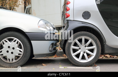 Bumper To Bumper - Two cars parallel parked on a street less than an inch from each other. Stock Photo