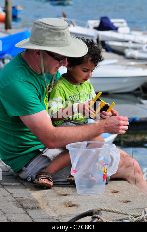 Father and son  fishing for crabs of f Victoria Quay Salcombe Town  Devon Stock Photo