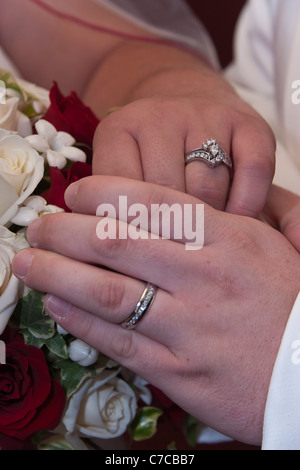 Newly wed couple holding hands and showing off their wedding bands Stock Photo