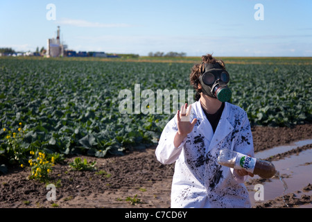 Woman wearing gas mask and holding poisoned water bottle; Camp Frack Protest Encampment & March against Hydraulic Water Fracturing & Shale-gas production at Becconsall, Banks, Southport. Stock Photo