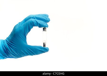 A gloved hand holding a syringe between two fingers Stock Photo