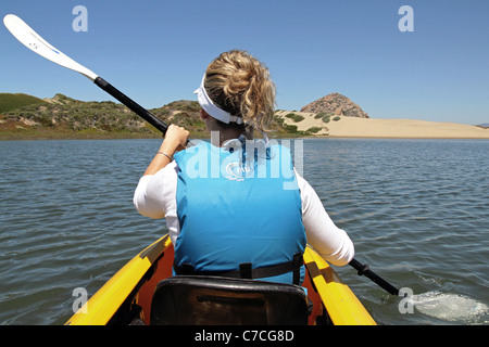 A woman kayaks in Morro Bay, California (Morro Rock is seen in the background) Stock Photo