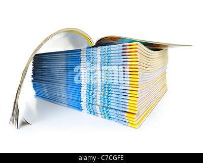 Many magazines stacked in a pile with one open isolated on white Stock Photo
