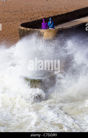 Two hoodies in the waves, two people watching the storm waves, Brighton, East Sussex, UK, autumn Stock Photo