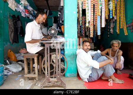 Asian man working on a sewing machine in a shop on a street in Old Delhi, India. Stock Photo