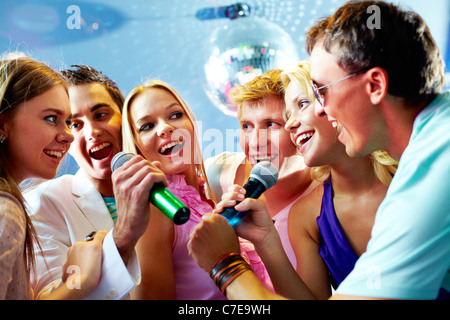 Portrait of joyous guys and girls singing at party together Stock Photo