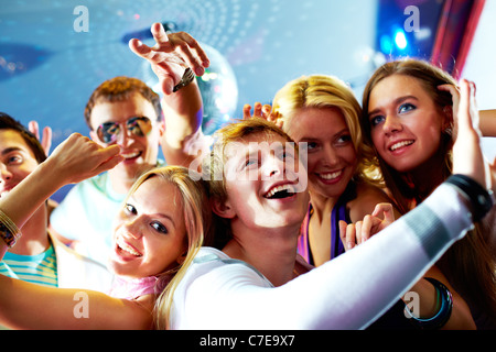 Portrait of glad guy dancing at party and laughing with friends on background Stock Photo