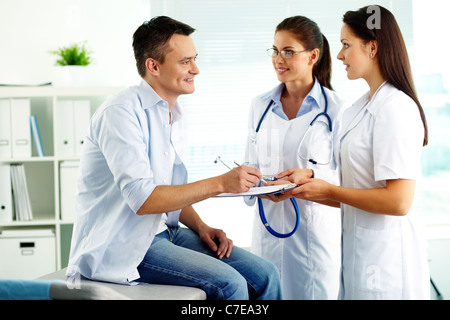 Portrait of confident female doctors and happy patient in hospital Stock Photo