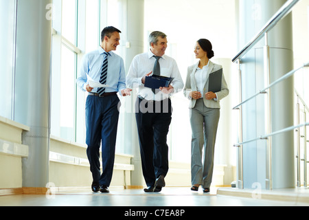 Confident business partners walking down in office building and discussing work Stock Photo