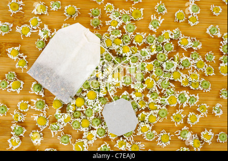Bag of chamomile tea with dry chamomilla flowers over wooden background - stillife Stock Photo
