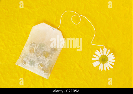 Bag of chamomile tea over yellow handmade paper - concept Stock Photo