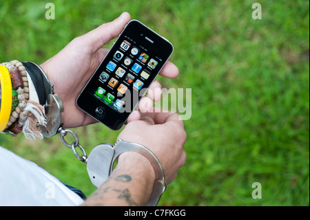Handcuffed teenager holding an Apple iphone. Stock Photo