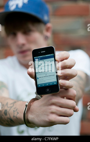 Handcuffed teenager holding an Apple iphone showing Facebook. Stock Photo