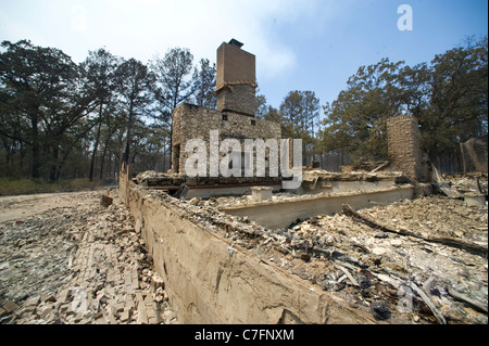 Foundation and partial wall of a burned-out home after wildfire swept through a semi-rural neighborhood in Bastrop Texas Stock Photo