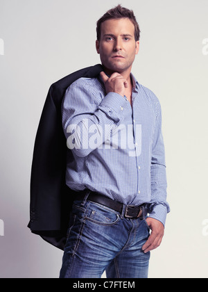 Casually with style dressed man in his thirties with a jacket over his shoulder Stock Photo