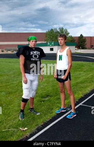 fraternal twin boys in athletic gear, ready for after school sports of football and track practice, standing at the ready Stock Photo