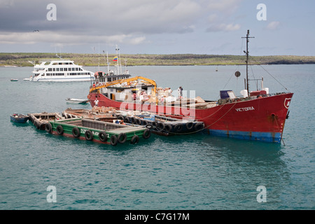 Supply boat Victoria unloading cargo onto a barge at Academy Bay, Puerto Ayora, Santa Cruz Island in the Galapagos Islands Stock Photo