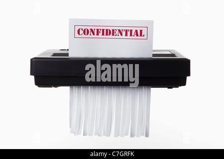 A document with CONFIDENTIAL on it being shredded in a paper shredder Stock Photo