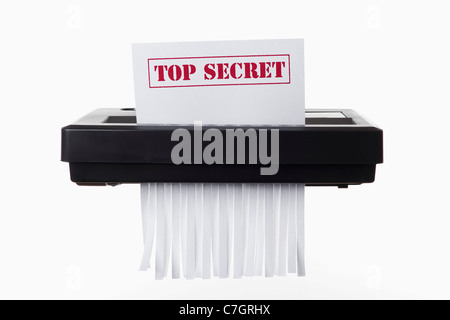 A document with TOP SECRET on it being shredded in a paper shredder Stock Photo