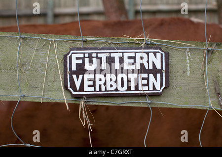 A FEEDING FORBIDDEN sign written in German hanging on a fence, close-up Stock Photo