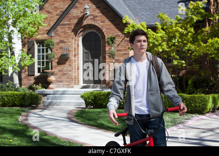 Boy standing still holding bike outside his house Stock Photo