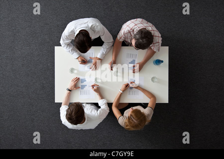 A business meeting with three businessmen and a businesswoman, overhead view Stock Photo