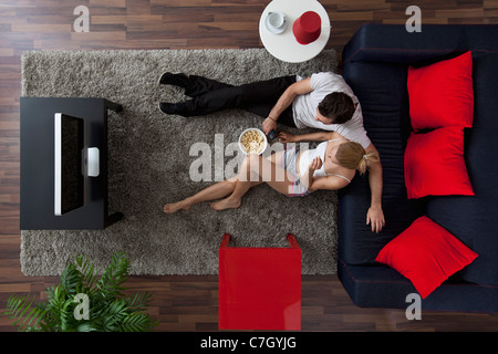 A couple eating popcorn and watching TV in their living room, overhead view Stock Photo