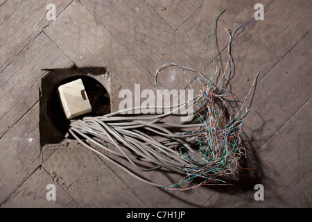 Cables coming out of a hole in a floor Stock Photo
