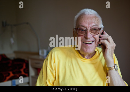 A cheerful senior man living in a nursing home, using a mobile phone Stock Photo