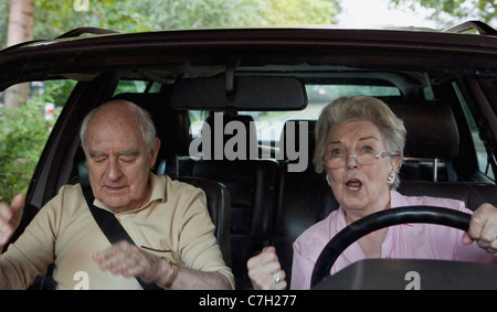 Woman learning to drive gets excited while man in passenger seat appeals for calm Stock Photo