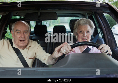 Woman has trouble driving while man in passenger tries to guide her hand Stock Photo