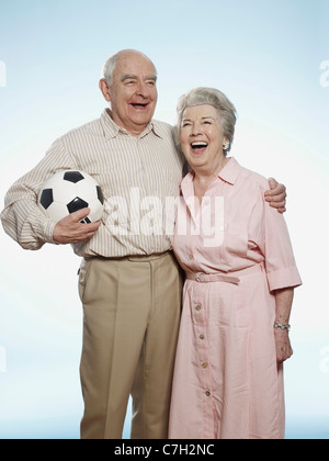 Senior couple laughing as man holds football Stock Photo