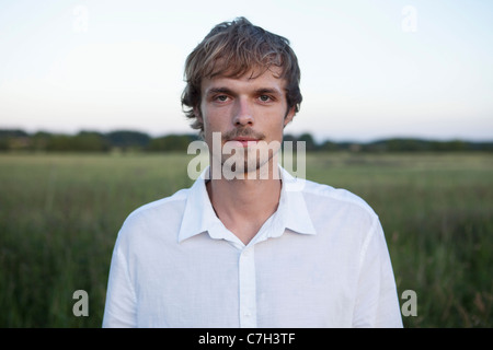Profile of man standing in field with white shirt on Stock Photo