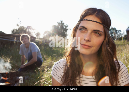 Profile of Long haired girl in field, and guy in the background looking at her Stock Photo