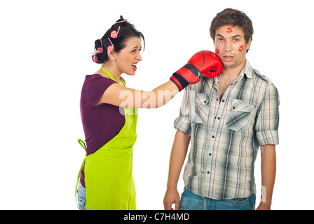 Crazy wife having conflict with surprised unfaithful husband and kick his face with boxing glove against white background Stock Photo