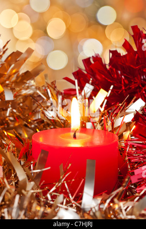Candle burning surrounded by Christmas Red and Golden Ribbons Stock Photo