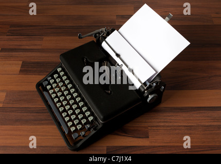 old portable typewriter with blank paper on the floor Stock Photo