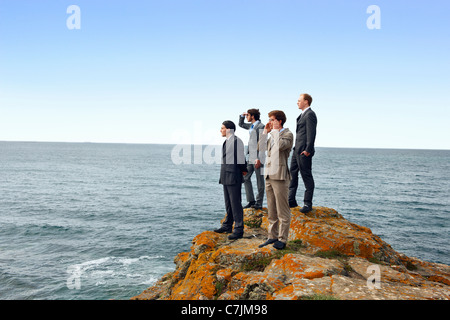 Businessmen standing on cliff edge Stock Photo