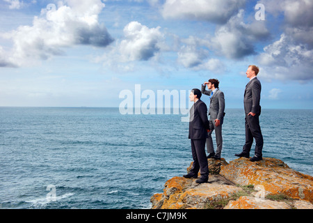 Businessmen standing on cliff edge Stock Photo