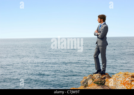 Businessmen standing on cliff edge Stock Photo